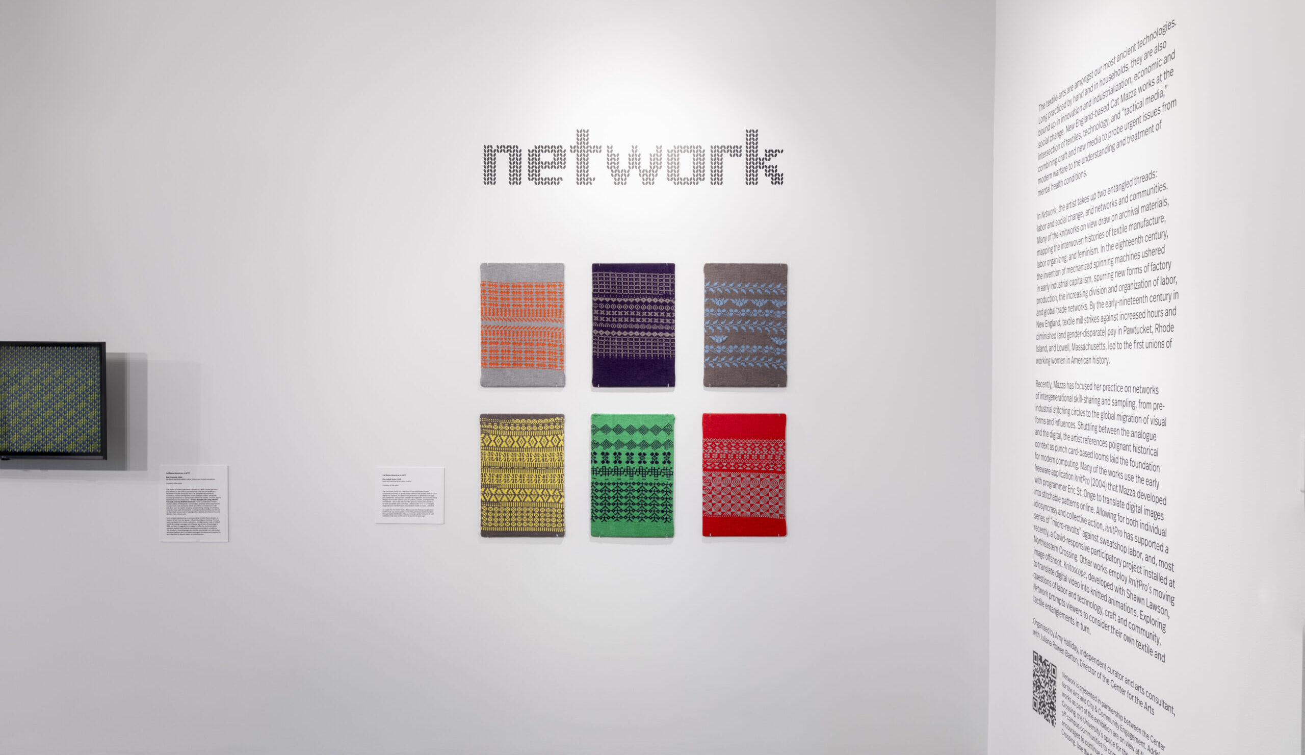 The image features a wall display of various abstract textile artworks by Cat Mazza. The central text on the wall reads "network," referring to the exhibition's themes around connectivity and technology. The artworks displayed are a series of rectangular panels, each featuring a distinct pattern or design in a variety of colors and styles, including geometric shapes, lines, and textures. The patterns were created with artist Cat Mazza's free web program, "Knitpro."